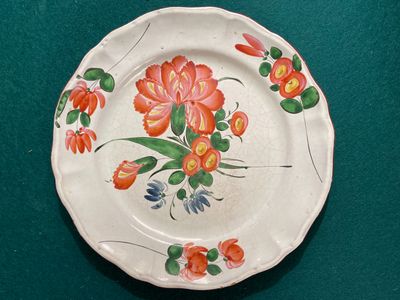 a plate with flowers painted on it on a green surface