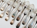a lot of silver spoons and forks on a white table