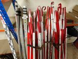 many skis and ski poles stacked on a shelf