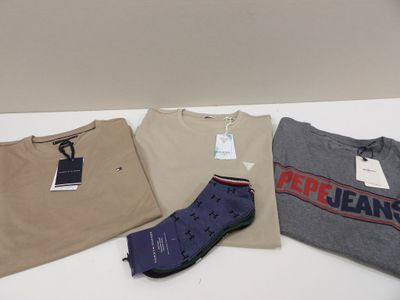 trois t-shirts pour homme et une paire de chaussettes posés sur une table