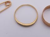 two gold rings and a safety pin on a table