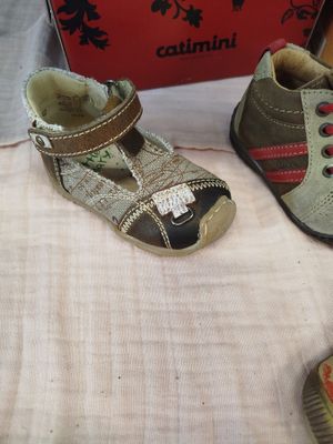 two pairs of shoes sitting on a bed next to a box
