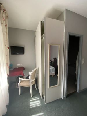 a room with a bed, a chair and a mirror in it
