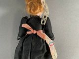 an image of a doll with a black dress and a brown hat