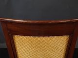 a close up of a wooden chair with a yellow upholstered seat