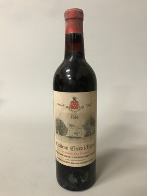 une vieille bouteille de vin rouge posée sur une surface blanche