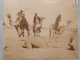 four men riding on camels in the desert