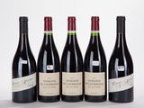 four bottles of wine are lined up on a white surface