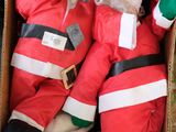 deux peluches représentant le Père Noël dans une boîte en carton