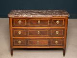 an antique chest of drawers with marble top and brass pulls