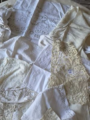 beaucoup de vêtements blancs posés sur un lit, à côté d'une table en bois