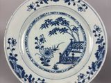 a blue and white plate with a picture of a man on a bench
