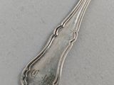 an old silver spoon sitting on top of a table next to a knife