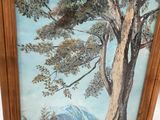 tableau représentant un arbre dans un cadre, avec une montagne en arrière-plan
