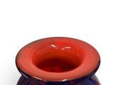 a red and blue vase sitting on a white surface