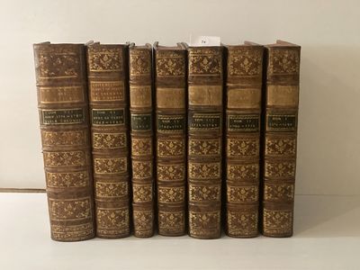 six vieux livres sont alignés sur une surface blanche
