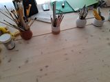a wooden table with a bunch of paint brushes and other items on it