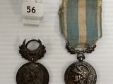 deux médailles et une médaille sur une surface blanche