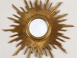 an image of a gold sunburst mirror hanging on a wall