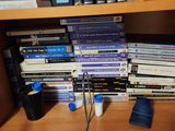 de nombreux DVD empilés sur une étagère à côté d'une lampe