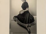 photographie en noir et blanc d'une femme en robe, assise sur un banc