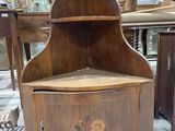 a wooden corner cabinet with a flower design on it
