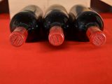 four bottles of wine are lined up on a red table