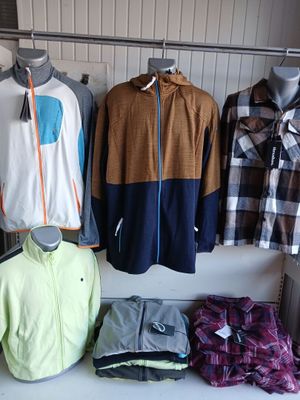 Plusieurs vêtements pour hommes sont présentés sur un portemanteau dans un magasin de vêtements