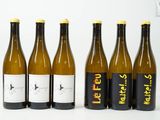 six bouteilles de vin sont alignées sur une surface blanche