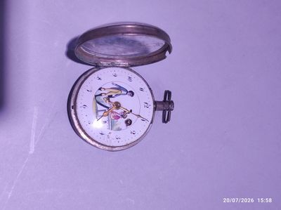 une petite montre de poche en argent sur laquelle est représenté un oiseau