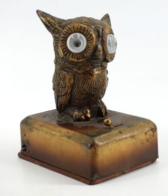 une statue de chouette en bronze posée sur un bloc de bois