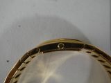 a close up of a gold bracelet on a white surface