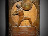 a bronze plaque depicting a man throwing a ball in the air