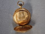 an image of a gold pocket watch sitting on top of a blue cloth