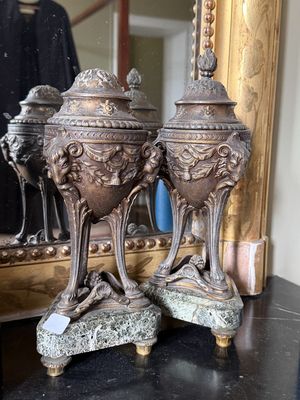 deux vases en argent posés sur une table devant un miroir