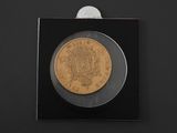 a gold coin on a black surface with a small coin in the center