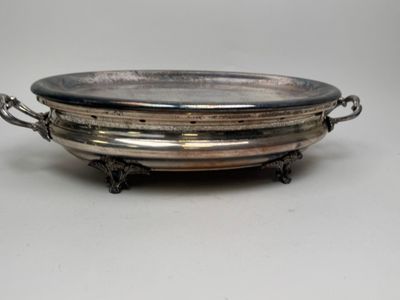 une assiette en argent ancienne avec des poignées et des poignées sur un support