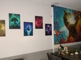 paintings on the wall of a living room with a table and chairs