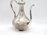 an antique silver tea pot with a handle on a white surface