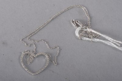a silver necklace with a heart and a bird on it