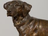 bronze statue of a dog with a collar standing on a pedestal