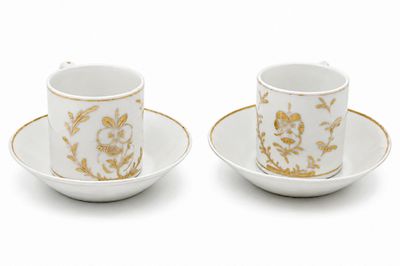 deux tasses et soucoupes ornées de motifs dorés sur fond blanc