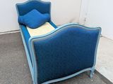 a blue bed with a blue pillow on top of it