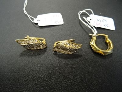 deux paires de boucles d'oreilles et un collier posés sur un fond noir