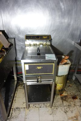 une photo d'une cuisine sale avec une cuisinière et une poubelle