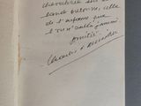 un livre ouvert, sur lequel est inscrit un poème manuscrit, posé sur une table