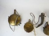 three antique brass bells on a white surface with a chain