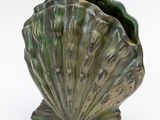 a large green shell shaped vase on a white surface