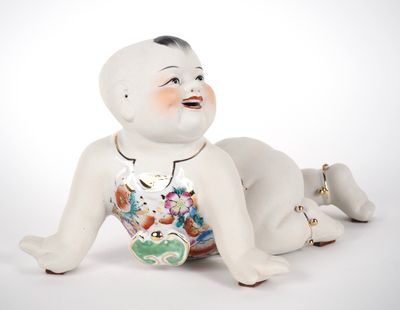 une figurine en porcelaine représentant un bébé allongé par terre