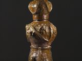 une statue en bronze représentant un homme assis sur une souche d'arbre